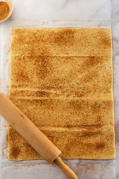 a wooden rolling pin sitting on top of a counter next to a piece of bread