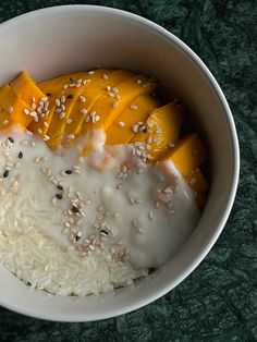 a bowl filled with rice, mango slices and sesame seeds