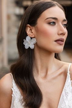 a woman with long hair wearing large flower earrings