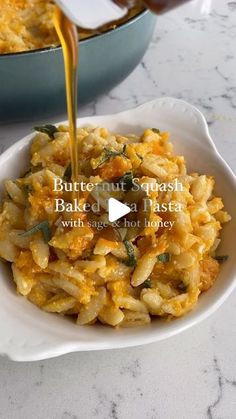 a bowl filled with pasta and sauce being poured into it on top of a table