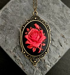 A beautiful red cameo with a dimensional rose on a black background set in antiqued brass paired with antiqued brass chain.  Details:  Pendant measures approx 2.5 inches in length Necklace measures 24 inches  Setting and chain are plated brass Cameo is hard, matte resin Please allow for possible slight color differences due to different settings on different screens. Want a shorter chain? Just leave a note to seller at checkout for me and I can adjust it for you, no extra charge. Thank you for shopping Delicate Industry :) Red Cameo Jewelry For Wedding, Red Cameo Jewelry Gift, Ornate Cameo Necklace For Gift, Red Cameo Necklace For Gift, Collectible Cameo Necklace With Round Pendant, Black Cameo Necklace, Marine City, Rose Rouge, Cameo Jewelry