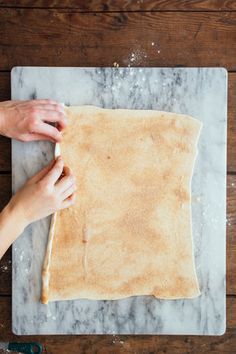 a person is kneading dough on top of a marble board with two hands