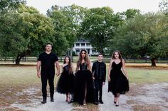 a group of people standing next to each other in front of some trees and grass