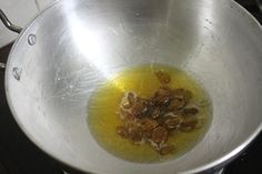 a metal bowl filled with oil and raisins on top of a stovetop