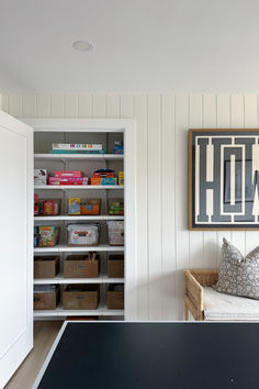 a ping pong table in the corner of a room with shelves and bins