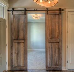 an empty room with two wooden doors and a chandelier hanging from the ceiling