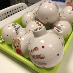 christmas ornaments are sitting in a green tray on the counter top, decorated with handwritten words