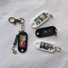 four different key chains are laying on top of a white sheet and one has an image of the same person