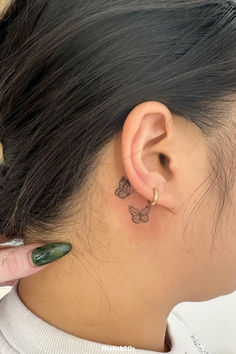 a woman's left ear has a small butterfly tattoo on it