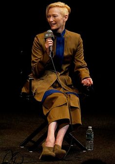 a woman sitting in a chair holding a microphone