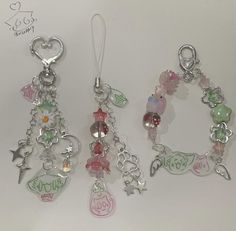 three charms are shown on a white surface, one is pink and the other is green