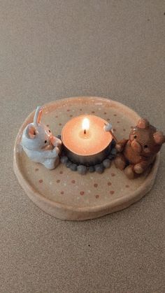 two little mice sitting on a plate with a lit candle in the shape of a heart