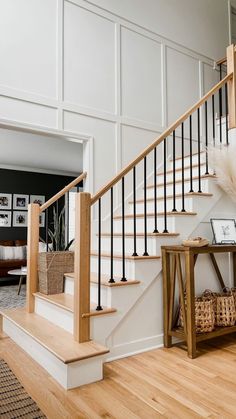 a white staircase with black railing and wooden handrails next to a coffee table