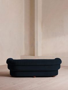 a black couch sitting on top of a hard wood floor next to a white wall