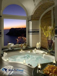 an indoor jacuzzi tub with candles on the side and water in the background