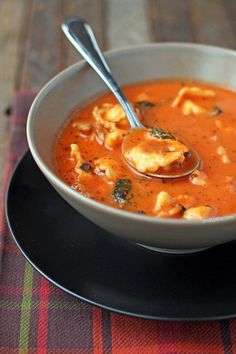 a spoon full of soup on top of a black plate