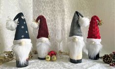 three gnomes are sitting on a table next to pine cones and other holiday decorations