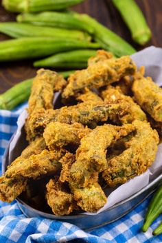 some fried food in a metal bowl on a blue and white checkered cloth