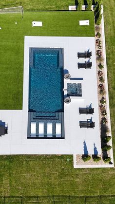 an aerial view of a swimming pool in the middle of a grassy area with chairs and tables