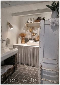 an open door leading to a bathroom with white walls and tile flooring, along with shelves on either side of the bathtub