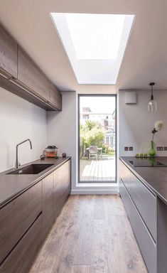 a kitchen with wooden floors and skylight above the counter top, along with stainless steel appliances