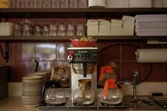 a coffee maker sitting on top of a counter next to stacks of plates and cups