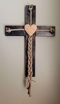 a cross with a wooden heart hanging from it's side and rope wrapped around the cross