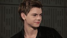 a close up of a person wearing a black shirt and necklace with an earring