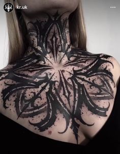 the back of a woman's neck with black ink on her face and chest