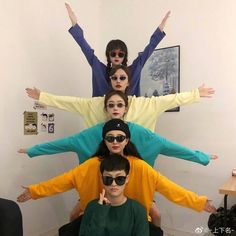 four people with their arms in the air and one person wearing sunglasses on his head