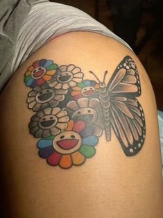 a butterfly and flowers tattoo on the back of a woman's arm with a teddy bear