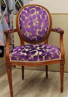 a purple and white chair sitting on top of a hard wood floor next to a wall