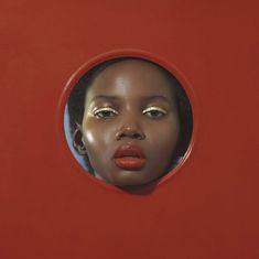 a woman's face is seen through a hole in a red wall with gold eyeshades