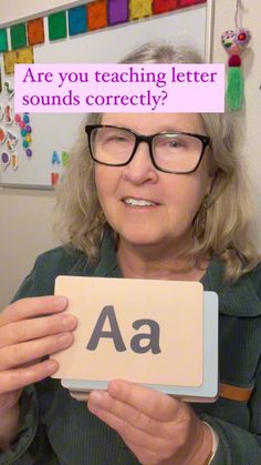 an older woman holding up a sign with the words are you teaching letter sounds correctly?