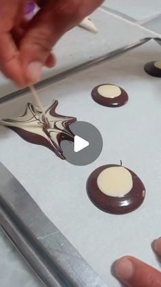 someone is decorating chocolates with white and brown icing