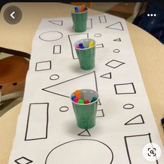 a table that has some cups on top of it with candy in them and the numbers drawn out