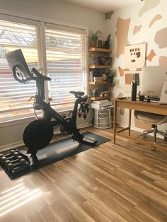 an exercise bike in the corner of a room with a desk and computer on it