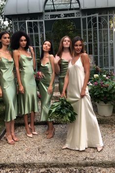 four women in green dresses are posing for a photo outside the glasshouse at their wedding