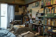 a bed room with a neatly made bed and bookshelves on the wall next to a window