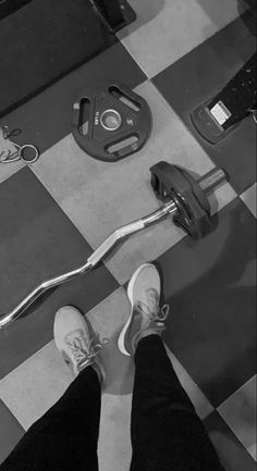 a person standing next to a barbell on a checkered floor