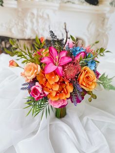 a bouquet of flowers is sitting on a white table cloth near a fire place in the background