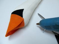 a pair of scissors is next to an orange and black pin cushion on a white surface