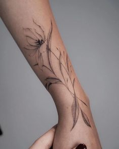 a woman's arm with a flower tattoo on the left side of her hand