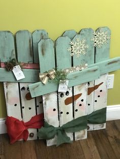 a snowman made out of old wooden boards with christmas decorations on it and attached to the fence