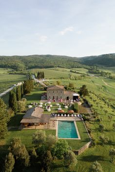 an aerial view of a large house in the middle of a field with a pool