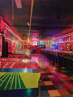 a brightly lit room filled with lots of tables and stools in front of colorful lights