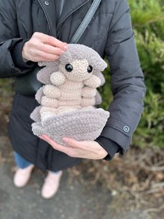 a person holding two small stuffed animals in their hands and one is wearing a coat