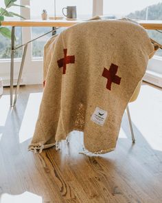 a blanket with red crosses on it sitting in front of a table next to a window