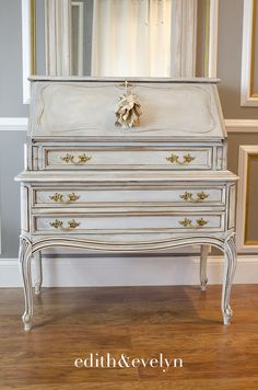 an antique dresser is painted white with gold trim