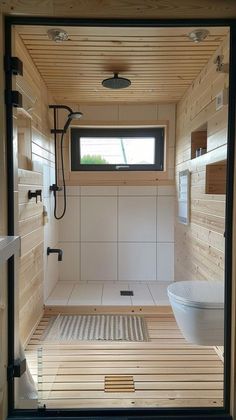 the inside of a small bathroom with wood flooring and white tile on the walls